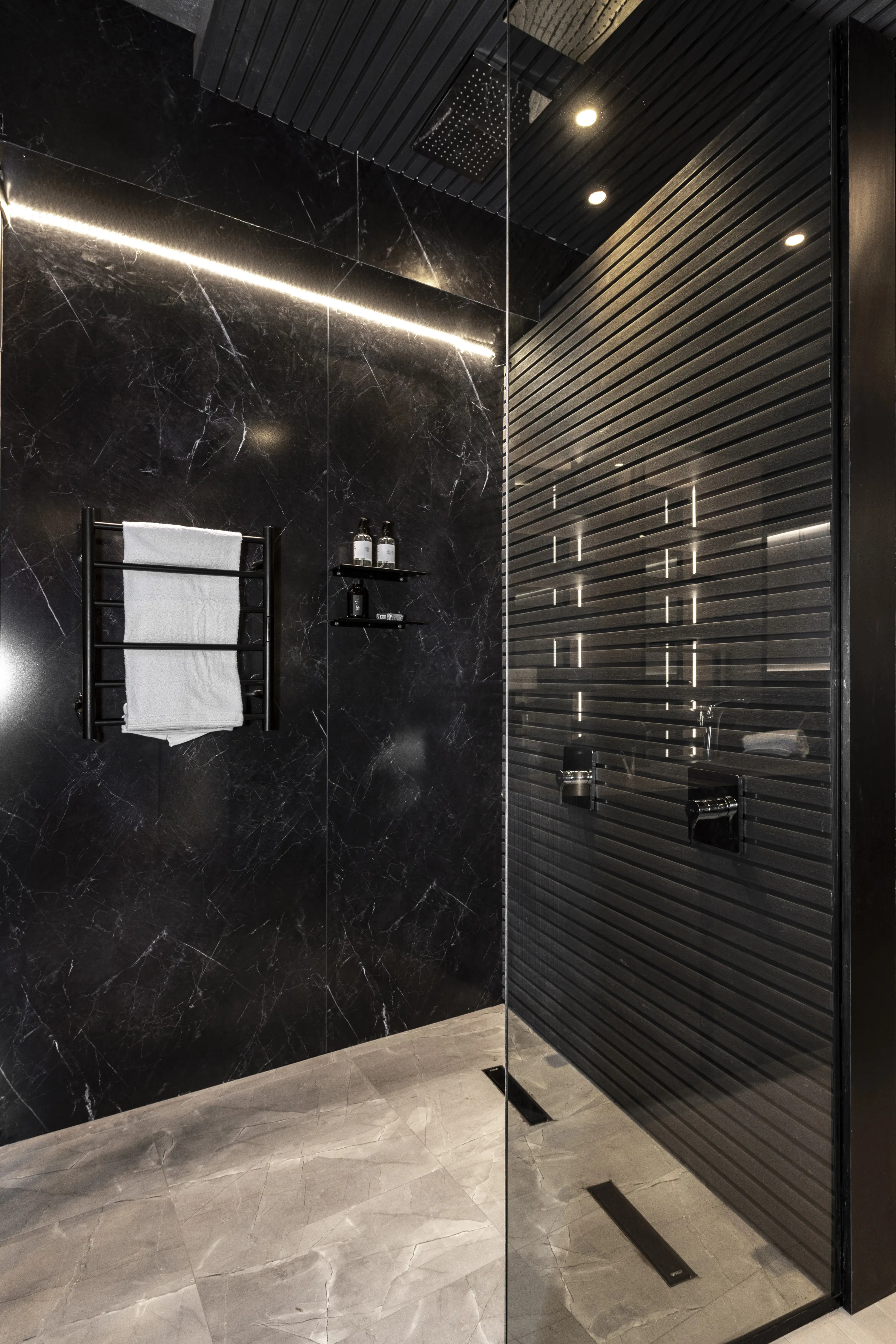 Estante para ducha Atrim instalado en baño moderno con revestimiento oscuro y toallas blancas