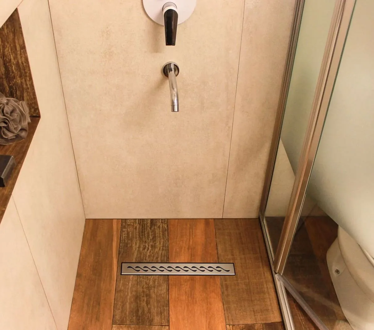 Desagüe lineal Atrim instalado en ducha con piso símil madera y mampara de vidrio