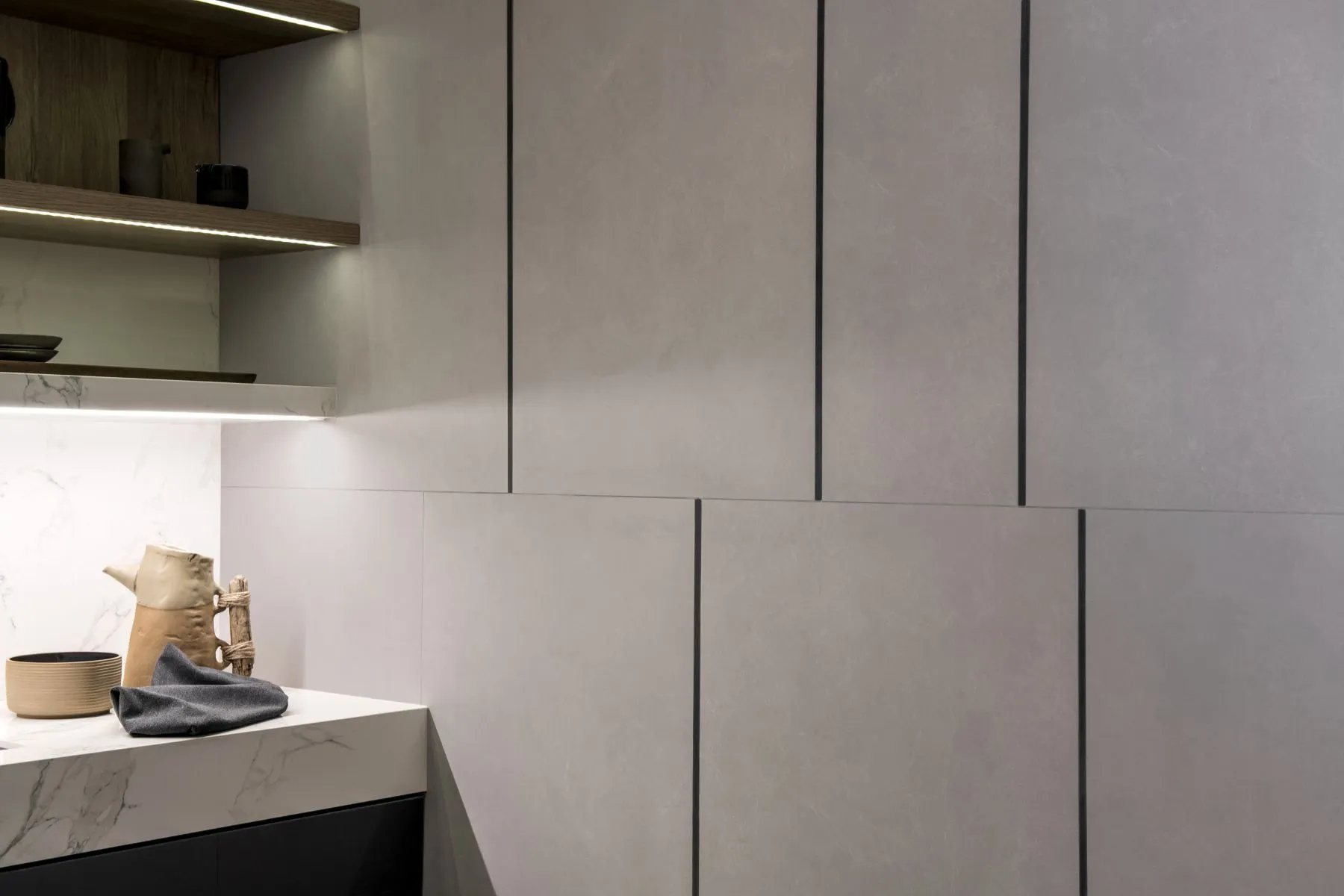 Perfil de aluminio Atrim instalado en pared de baño con revestimiento gris, ideal para crear líneas decorativas y una terminación moderna