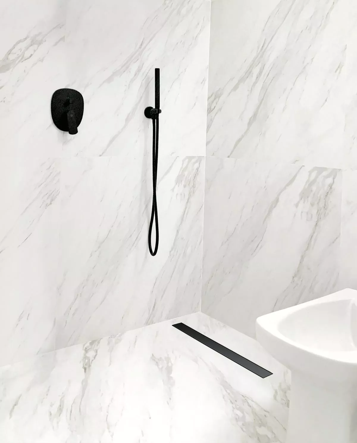 Ducha moderna con revestimiento símil mármol, grifería negra y desagüe lineal en el piso